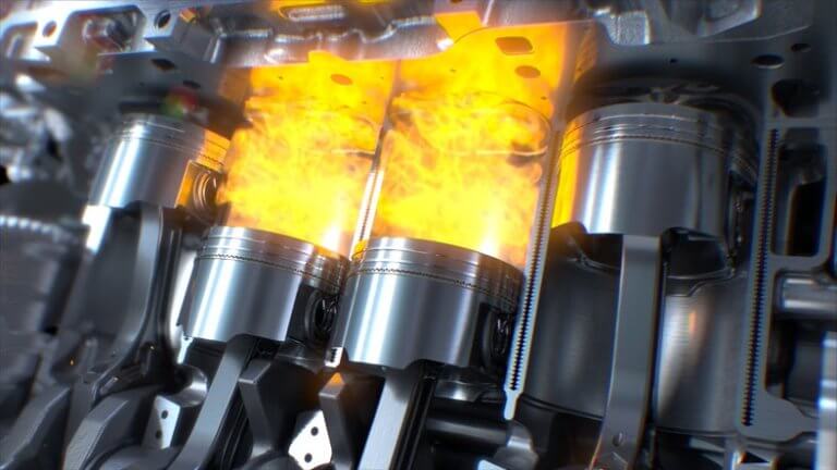 A close-up of an engine's internal combustion process, showing metal pistons and connecting rods in motion. Flames are visible above the pistons, illustrating the ignition and power stroke inside the engine's cylinders.