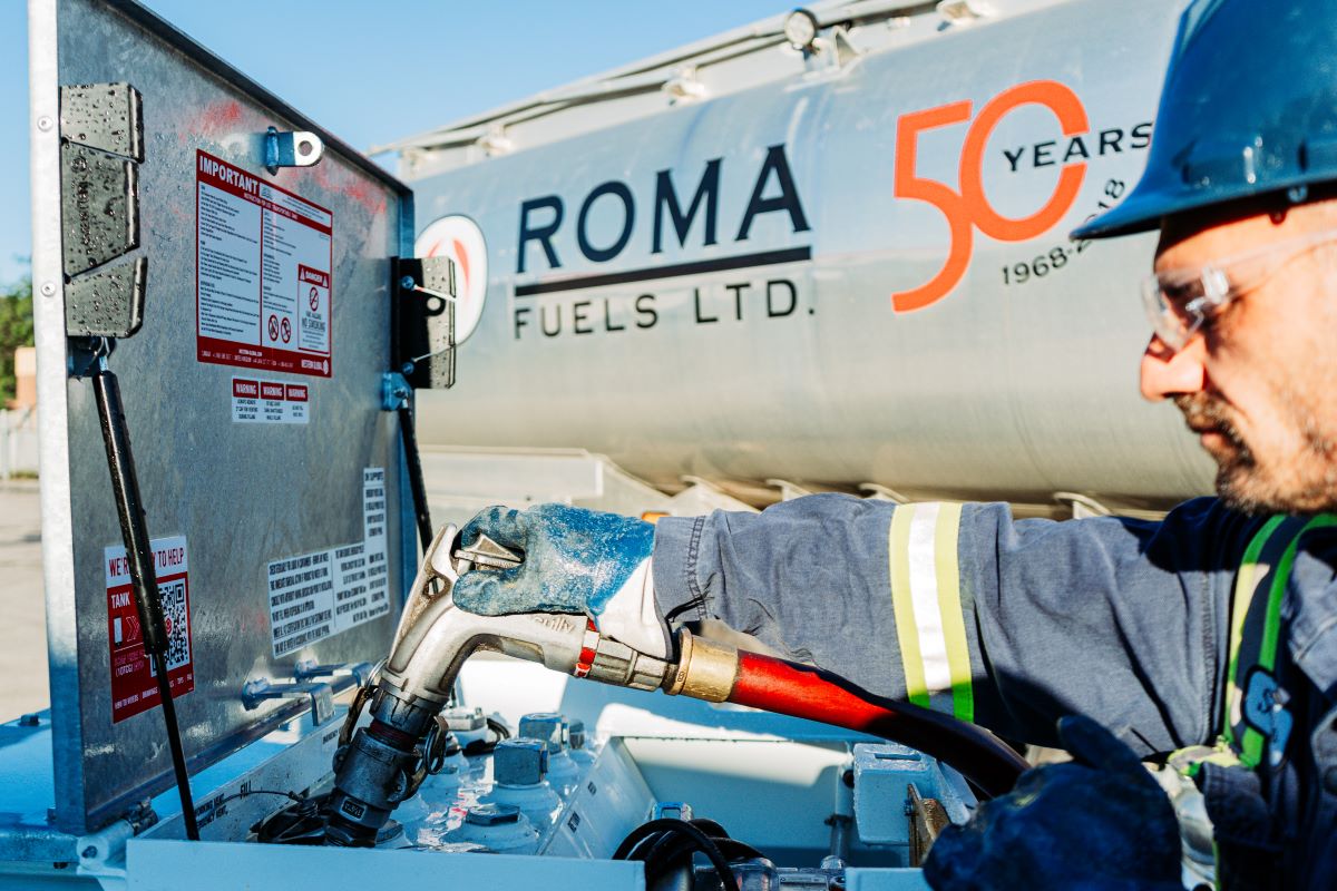 A man wearing a hard hat and safety glasses is diligently refueling construction machinary.